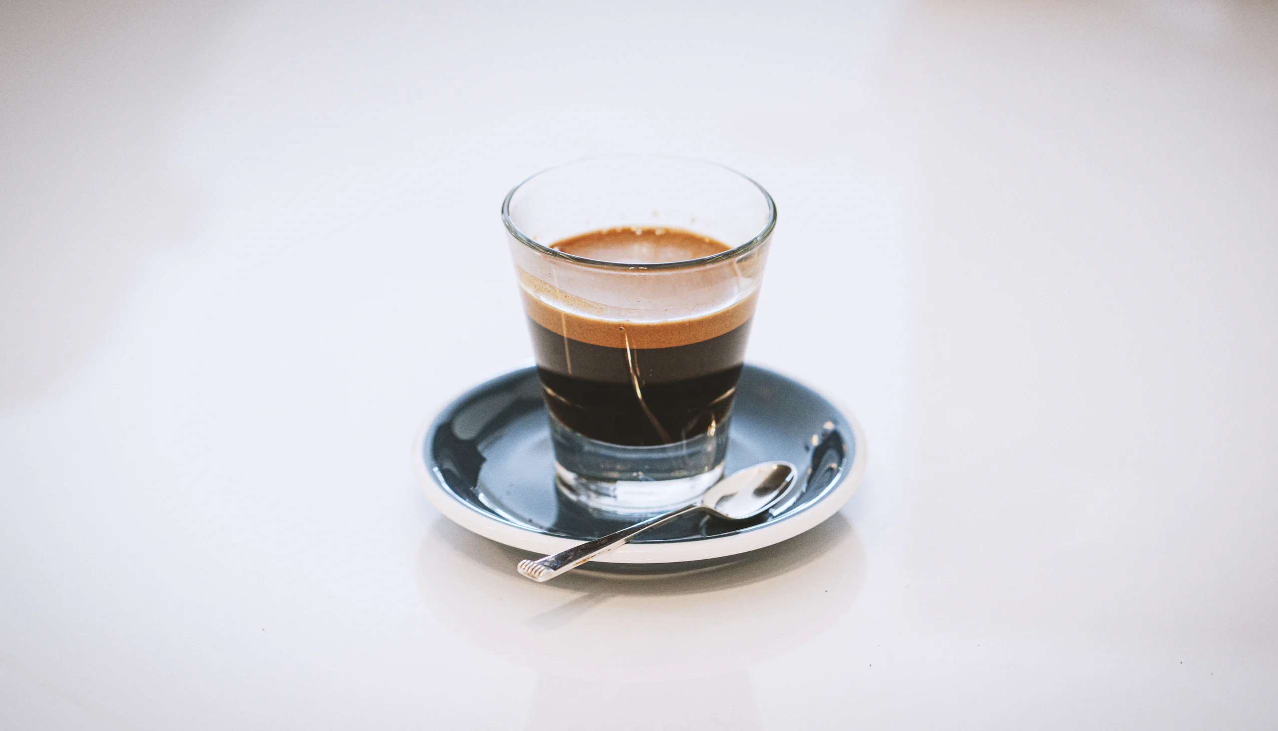 Espresso în pahar de sticlă, pe farfurioară, lumină curată