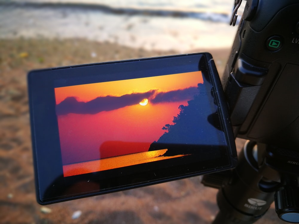 black tablet computer turned on displaying orange and blue sky