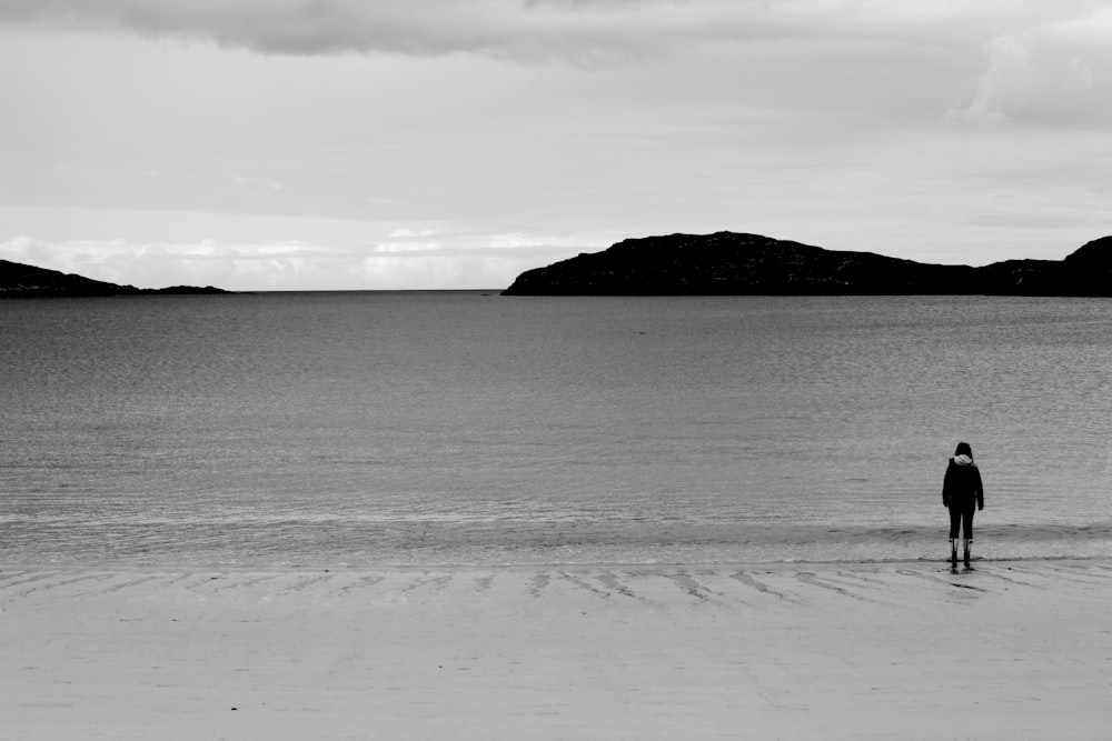 body of water near mountain under white clouds during daytime