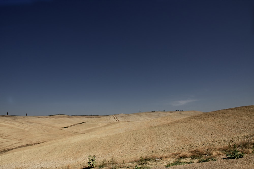 brown sand field under blue sky during daytime