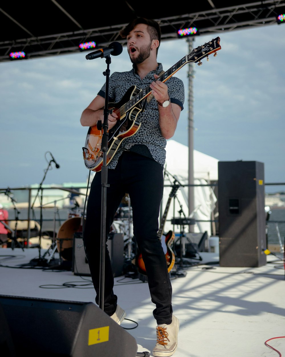 man in black and white tank top playing guitar