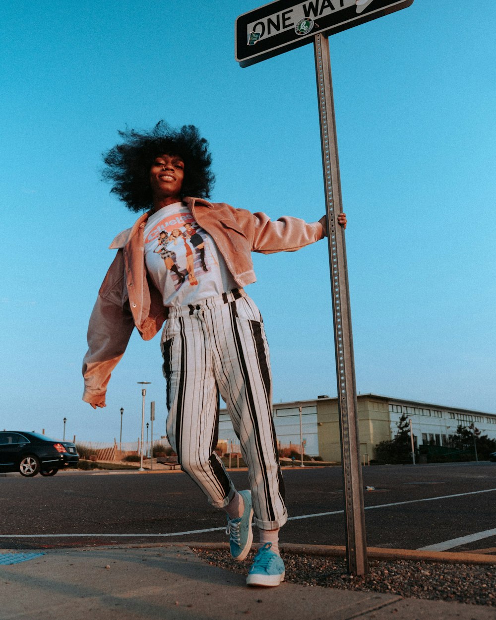 woman in white and red long sleeve shirt and white pants standing on street during daytime