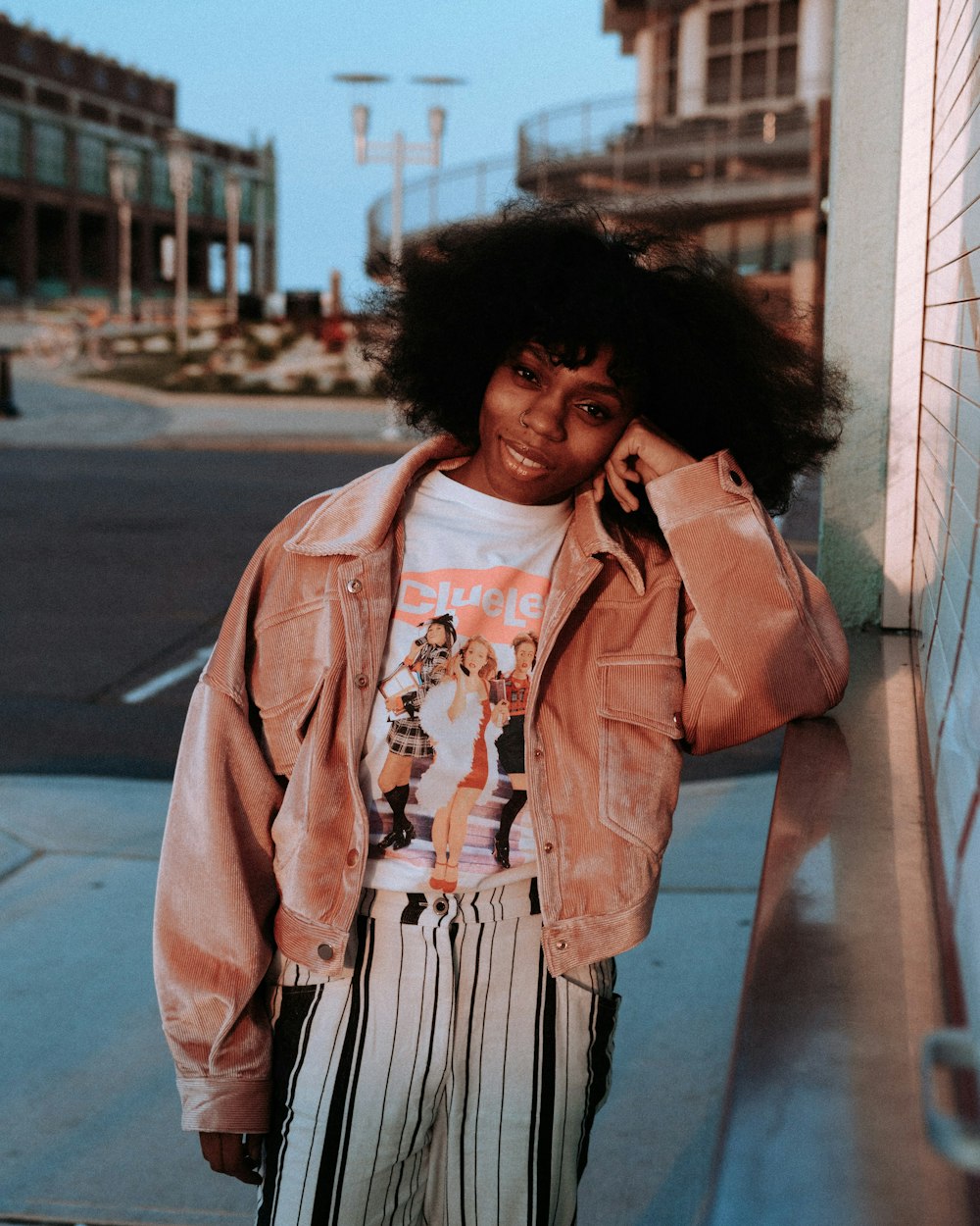 woman in pink coat standing on sidewalk during daytime