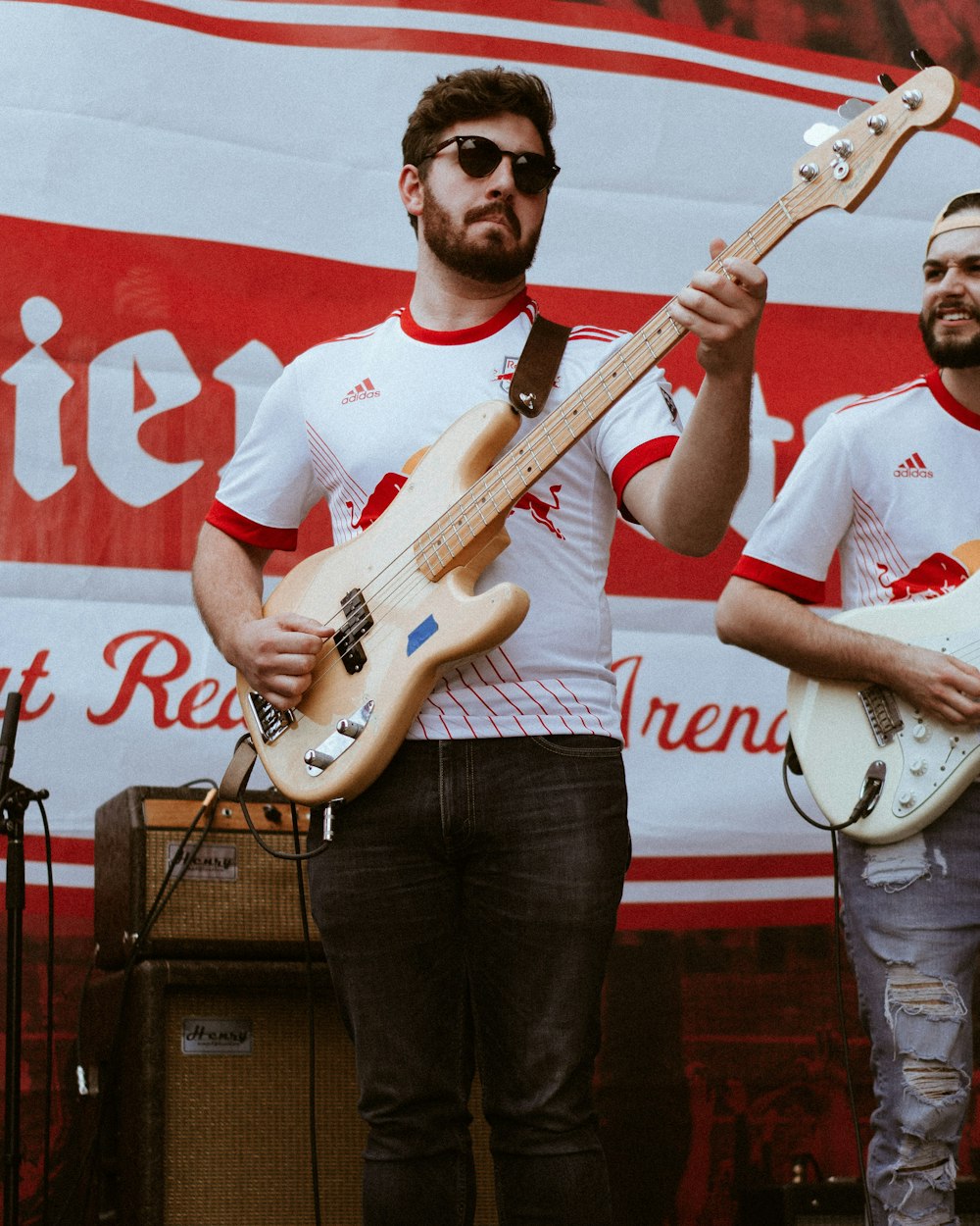 man in red crew neck t-shirt holding white electric guitar