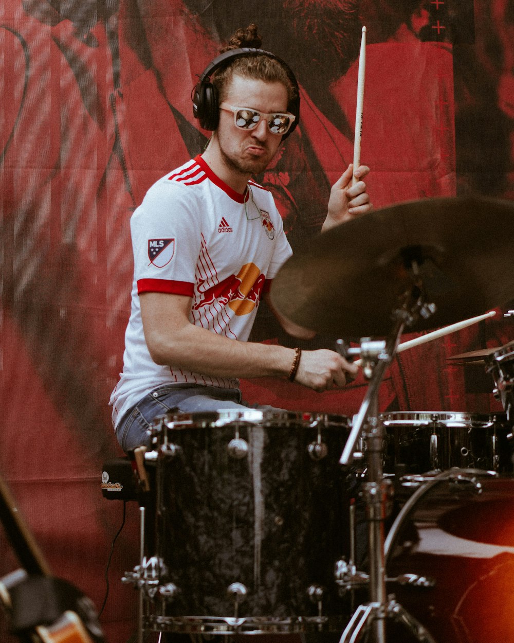man in white and red crew neck t-shirt playing drum