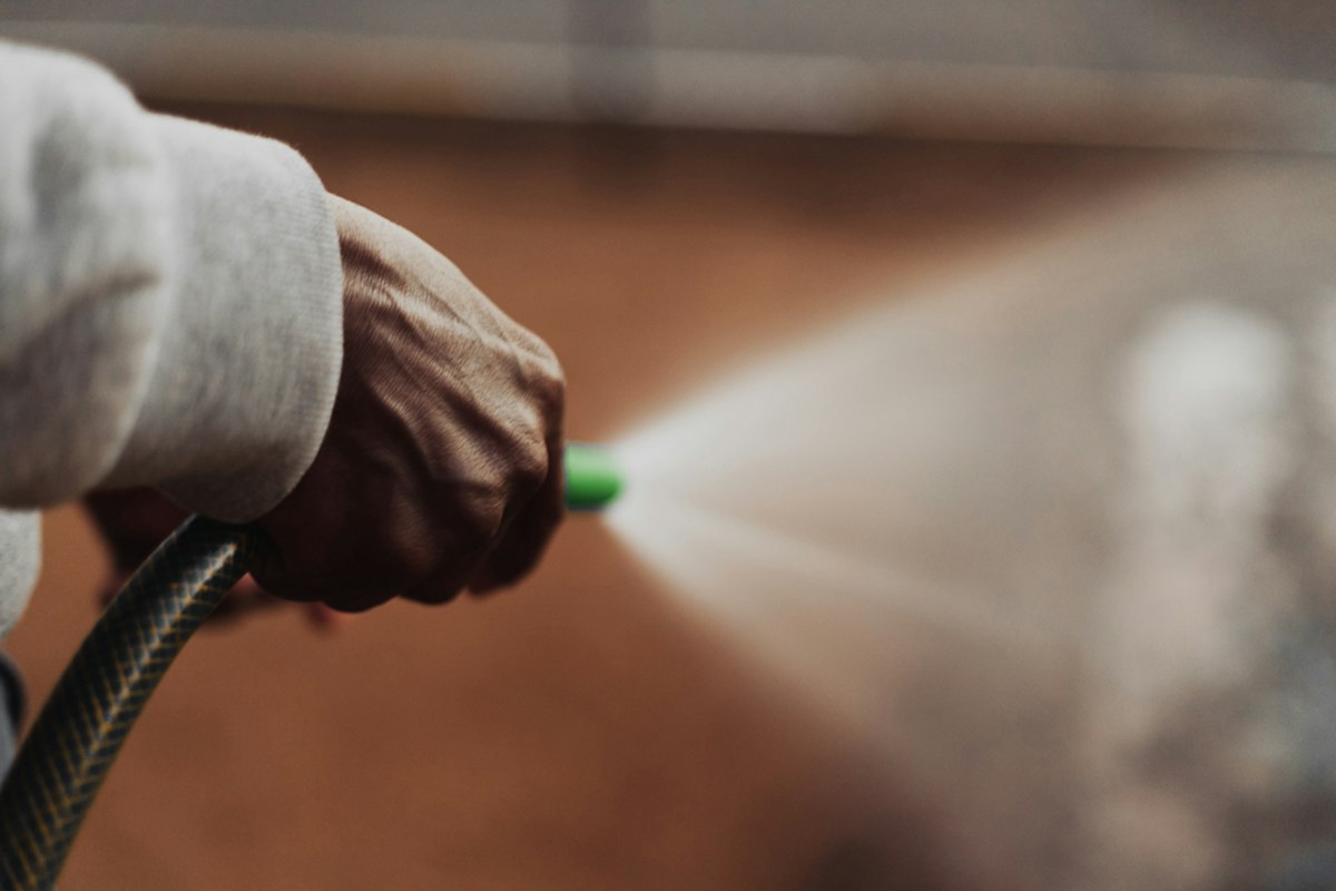 Close-up of a pressure washer nozzle spraying an exterior surface
