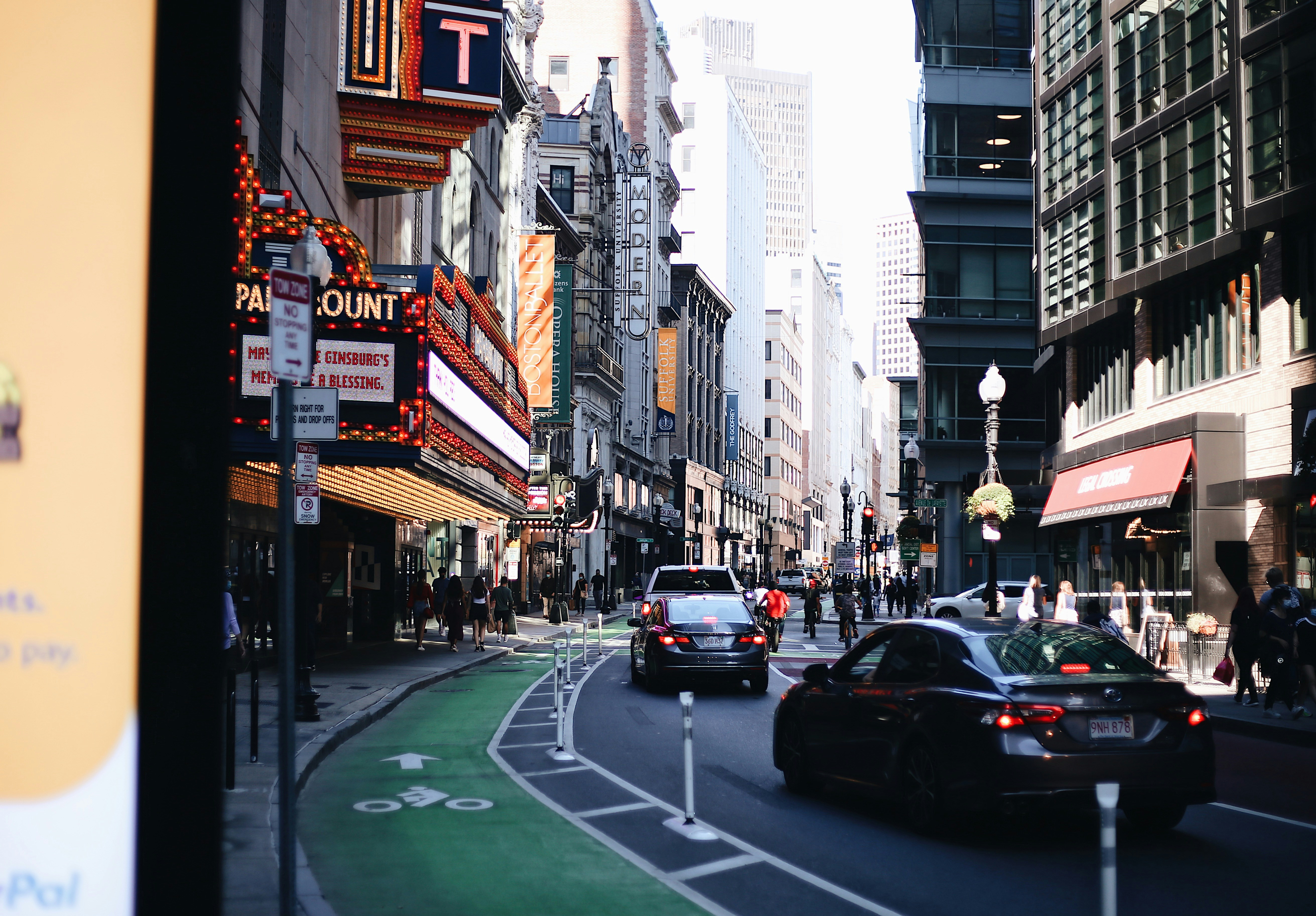 cars on road between high rise buildings during daytime