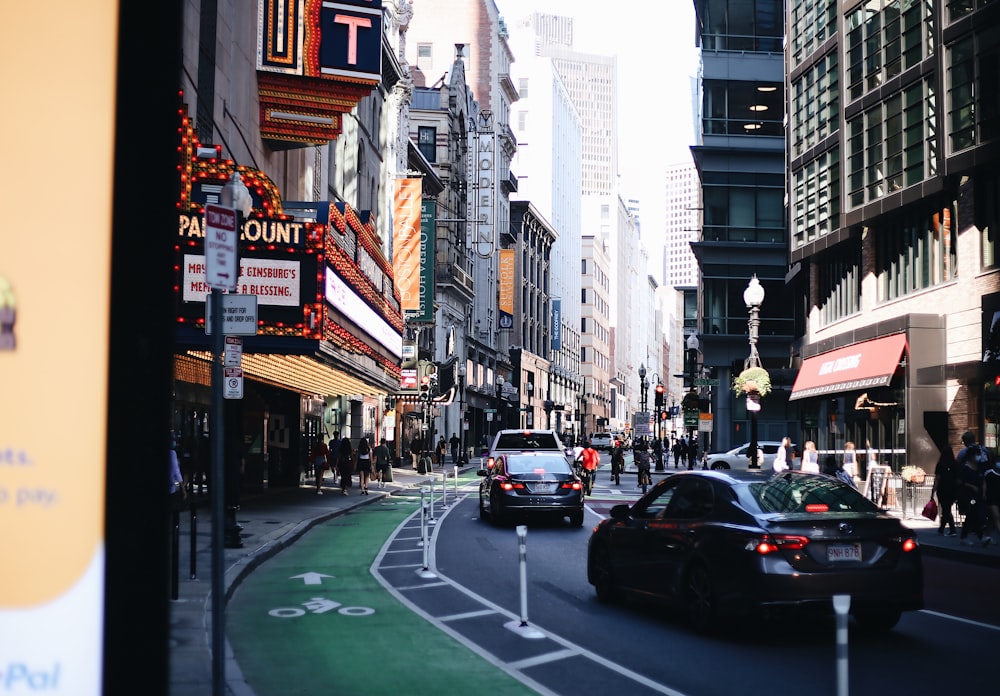 cars on road between high rise buildings during daytime