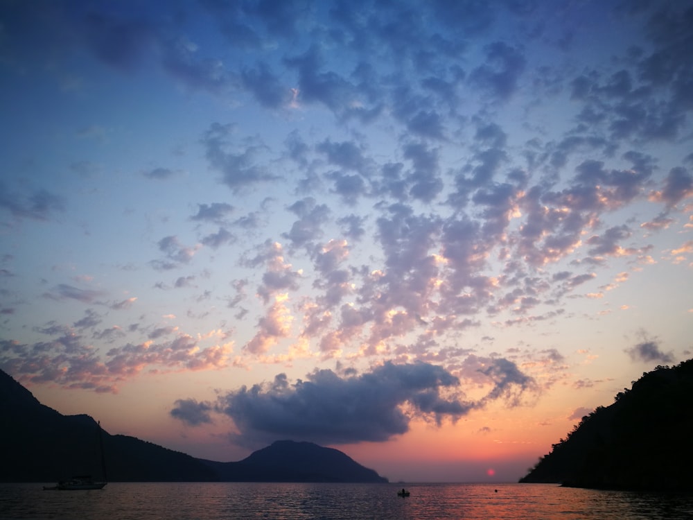 silhouette of mountain under cloudy sky during sunset