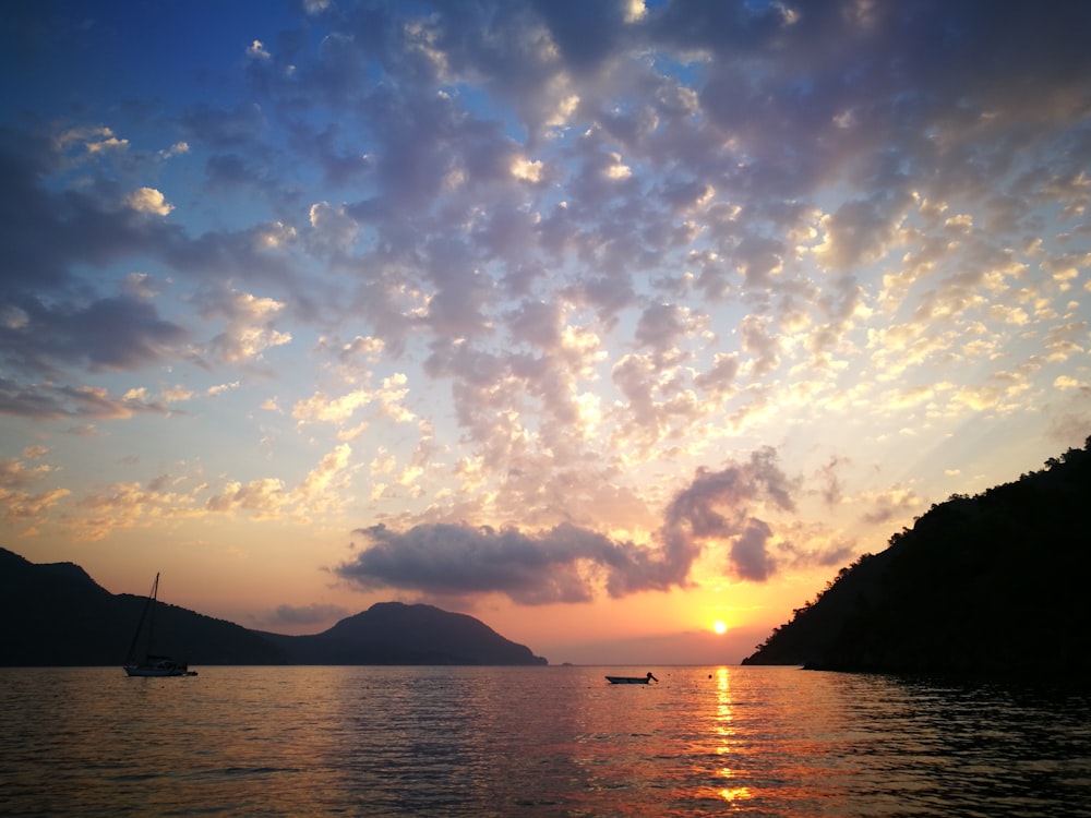 silhouette of mountain near body of water during sunset