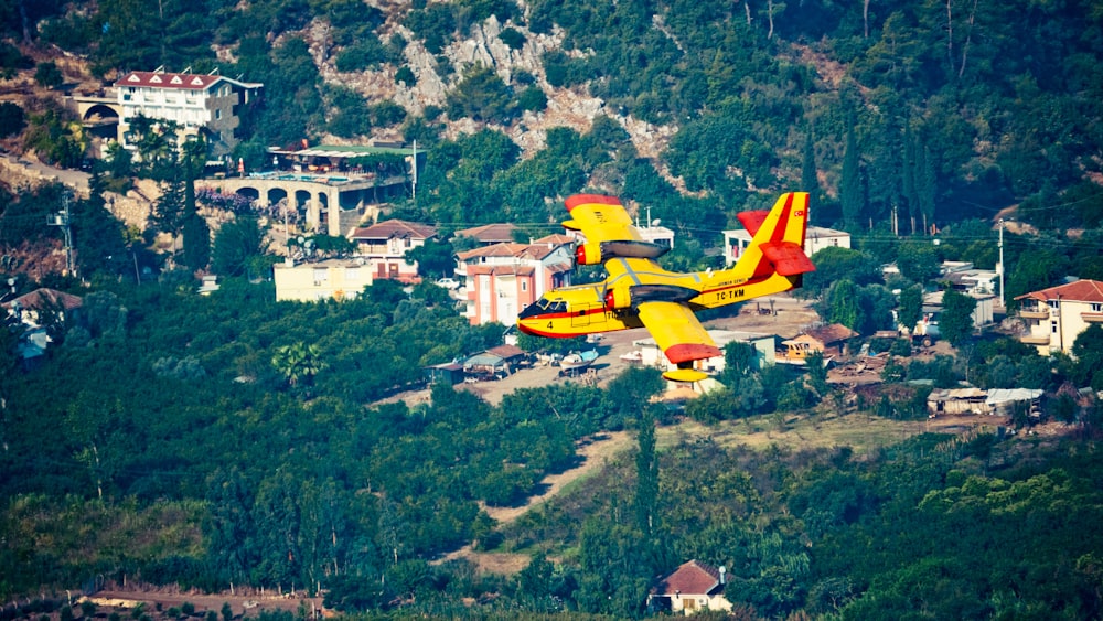 avião amarelo e vermelho voando sobre o campo de grama verde durante o dia