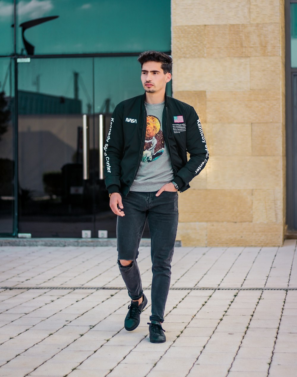 man in black jacket standing on gray brick floor