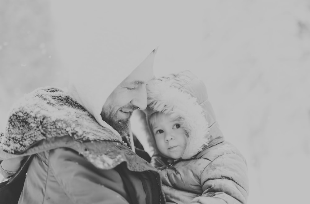 grayscale photo of baby in white knit cap and jacket