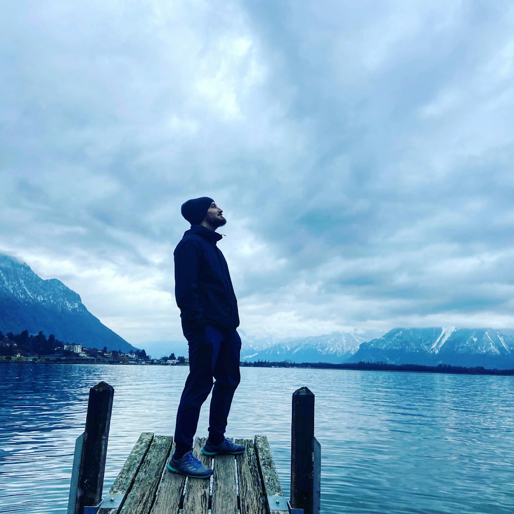 man in black jacket standing on wooden dock during daytime