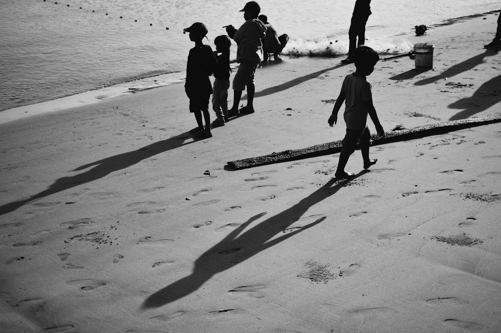 Siluetta delle persone che camminano sulla spiaggia durante il giorno