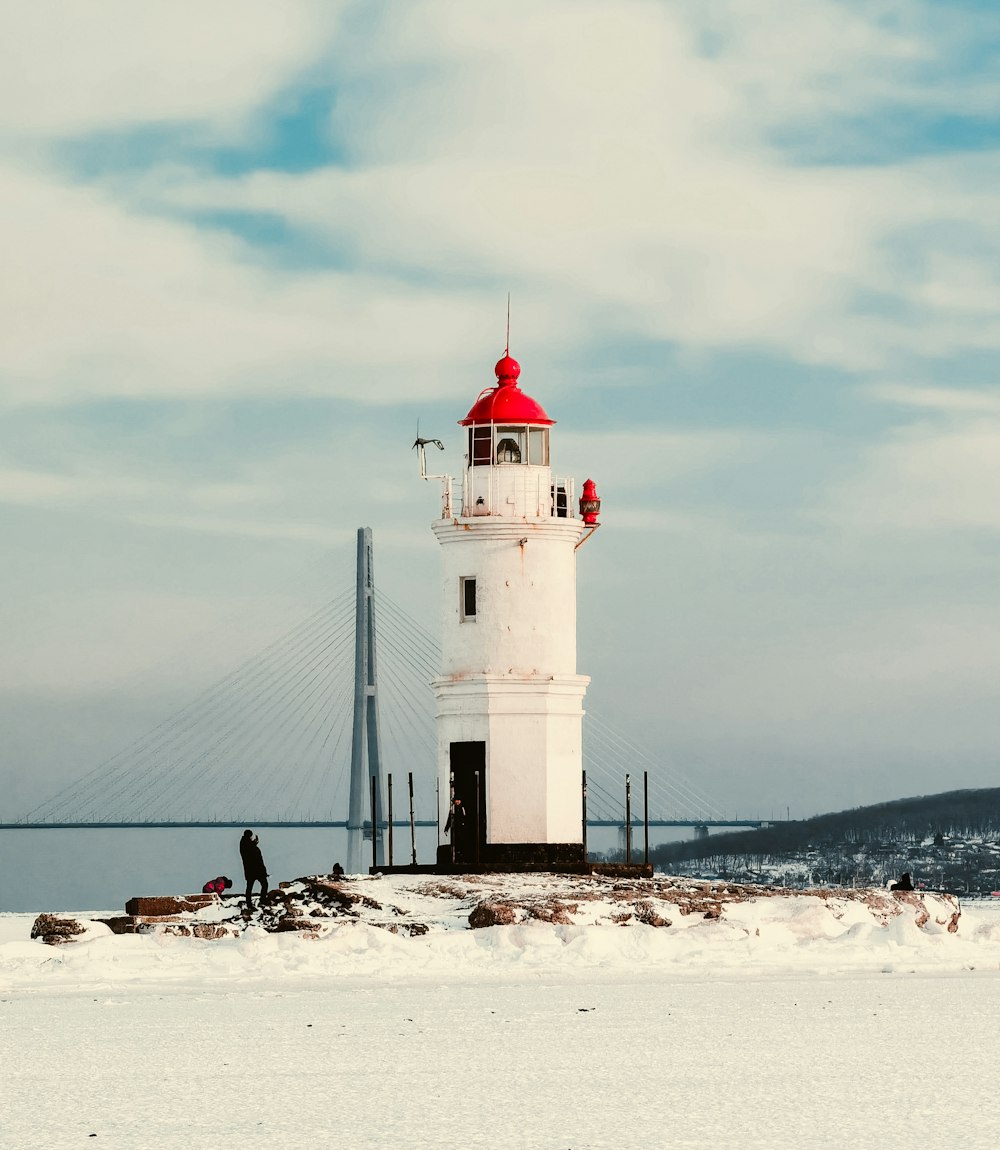 white and black lighthouse on white sand under cloudy sky during daytime