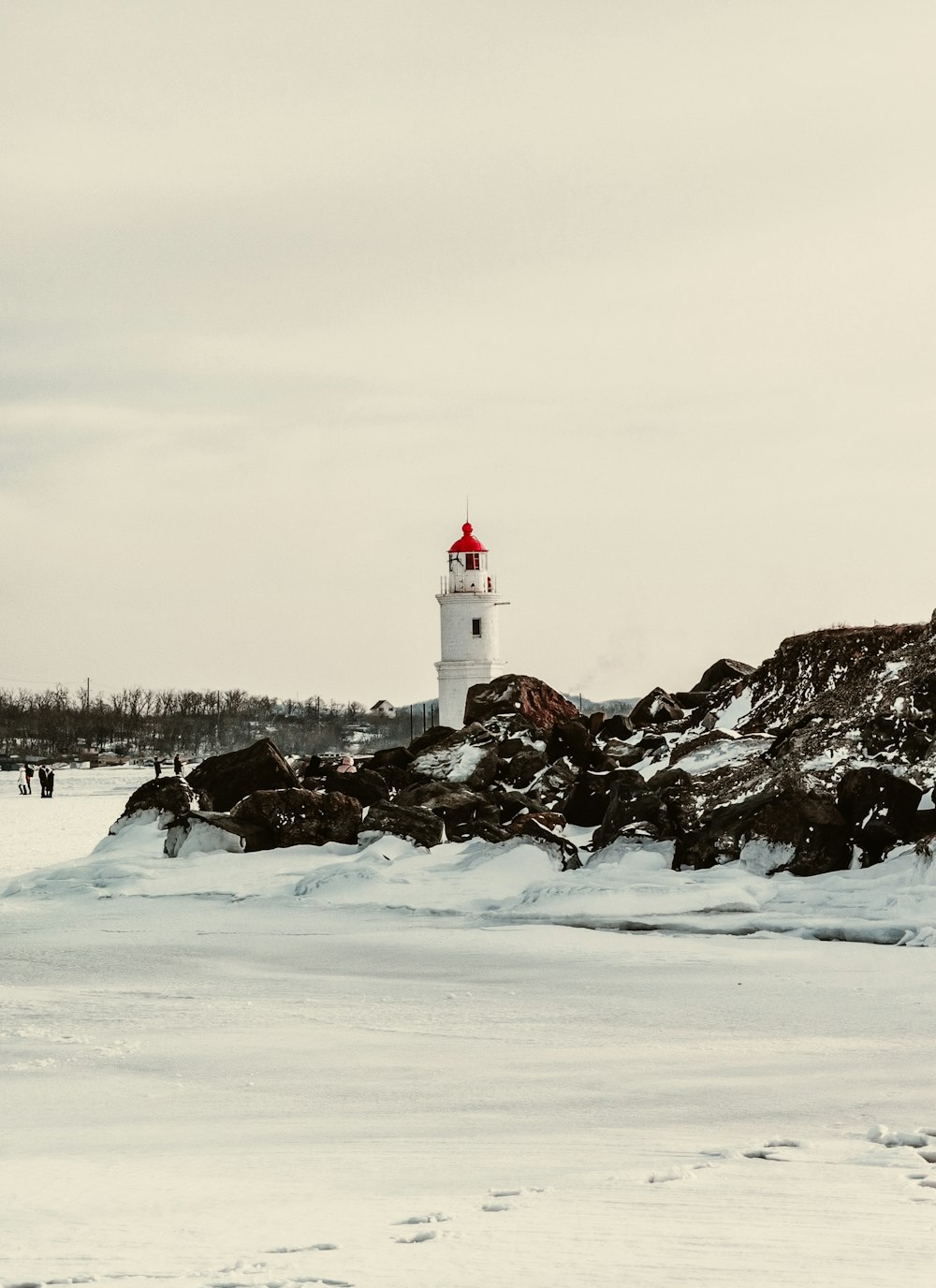 昼間の雪に覆われた地面に白い灯台