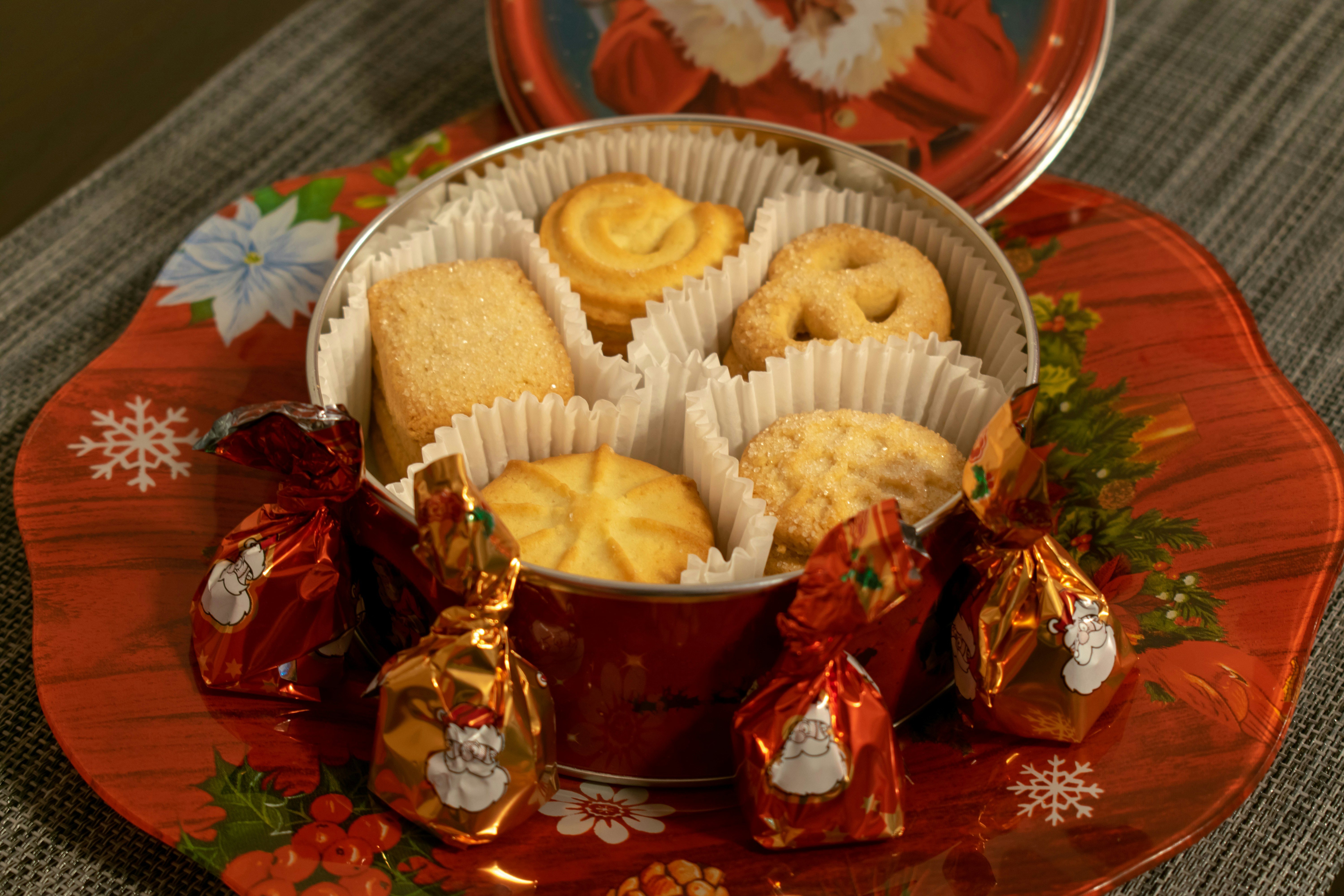 Decorative tin filled with festive holiday cookies including gingerbread and sugar cookies