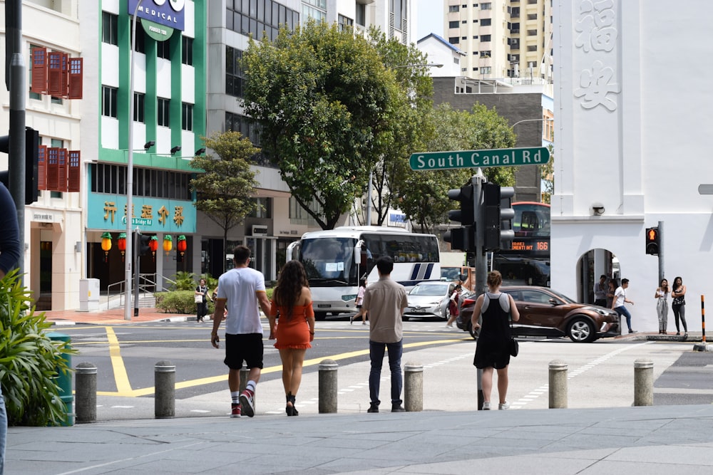 woman in orange jacket walking on pedestrian lane during daytime