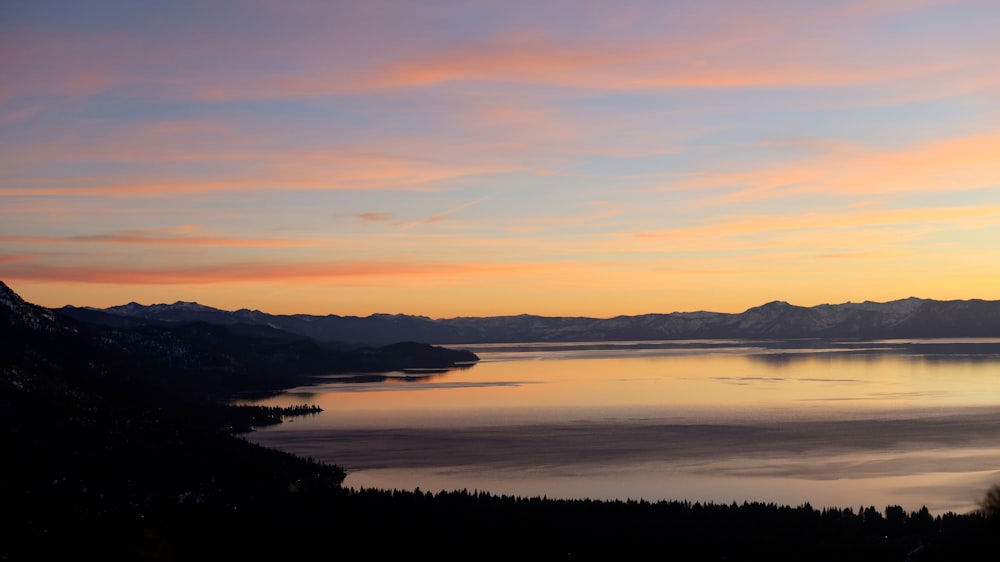 body of water near mountain during daytime