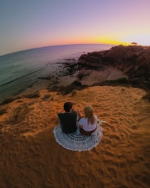 man and woman sitting on brown rock formation during daytime