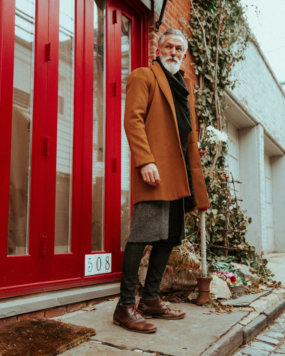 woman in brown coat standing near red wooden door