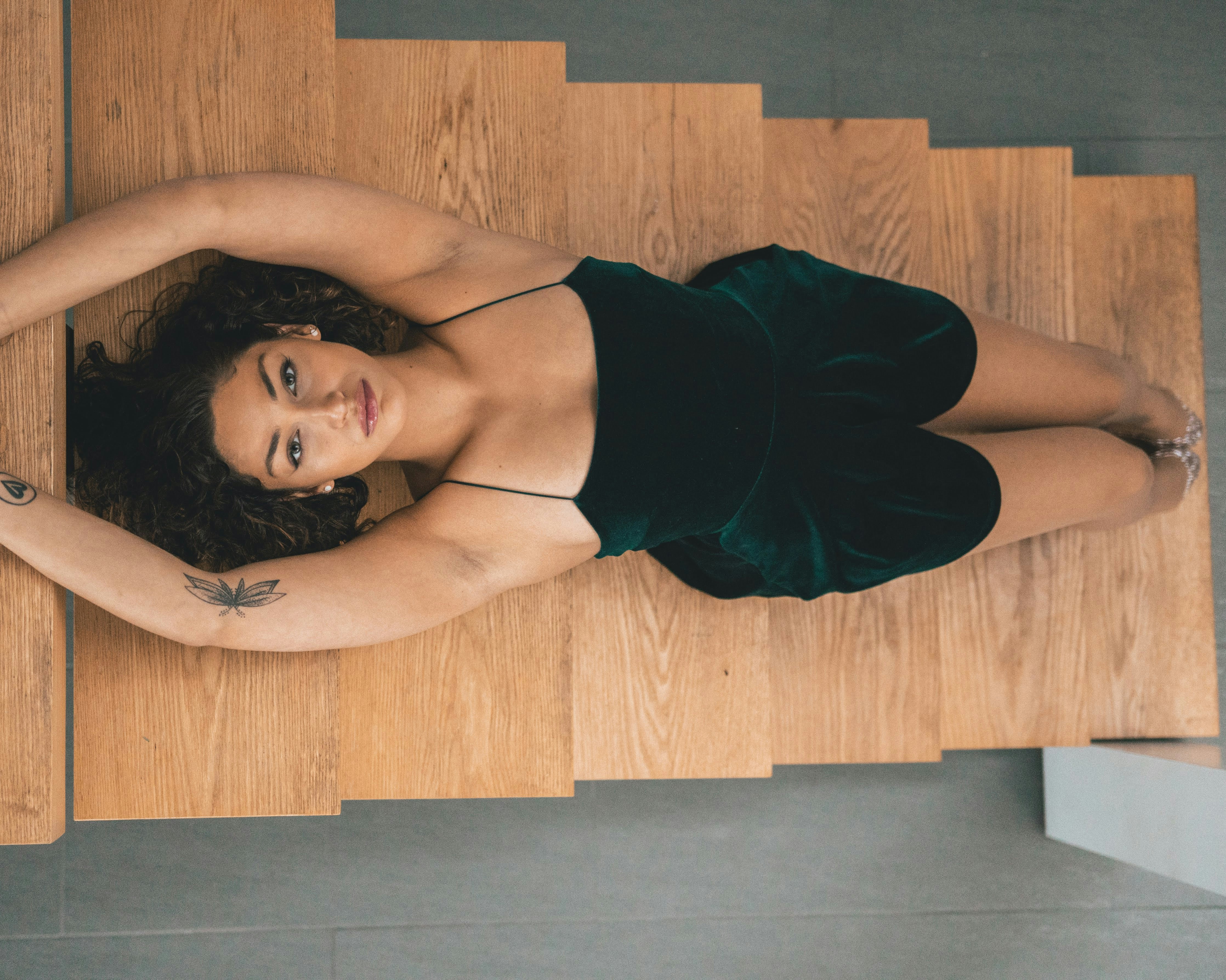 woman in black spaghetti strap top lying on brown wooden floor