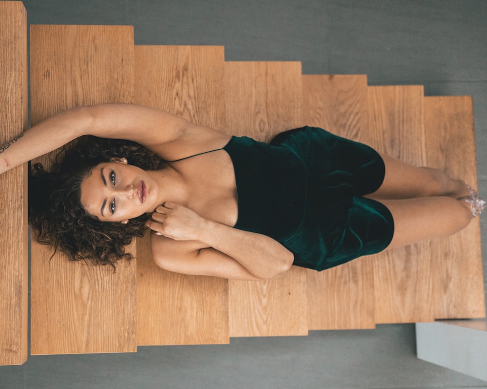 woman in black tube dress lying on brown wooden floor