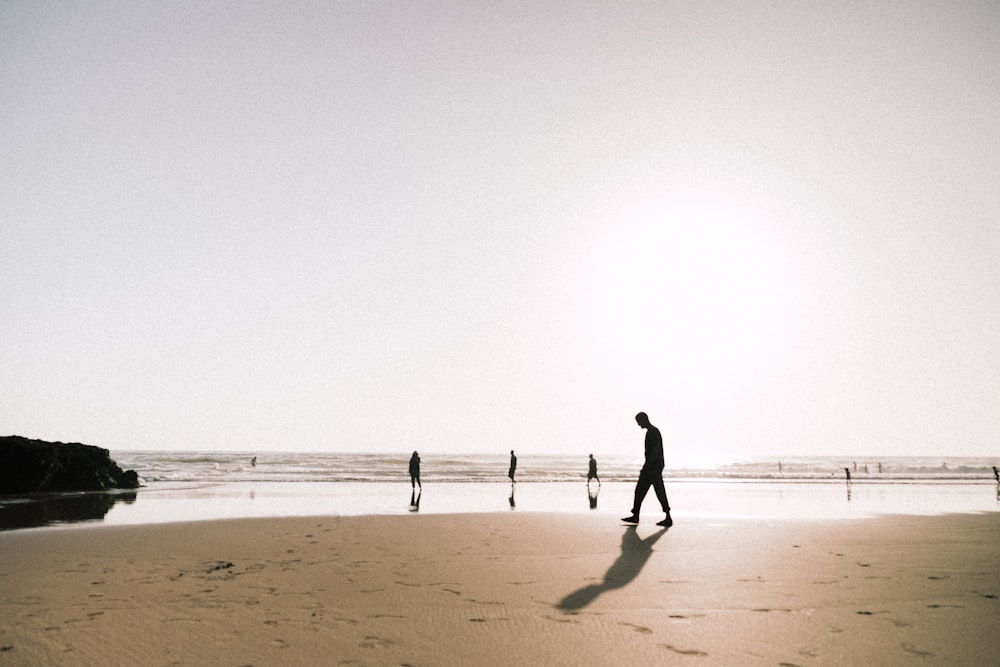 silhouette of man walking on beach during daytime