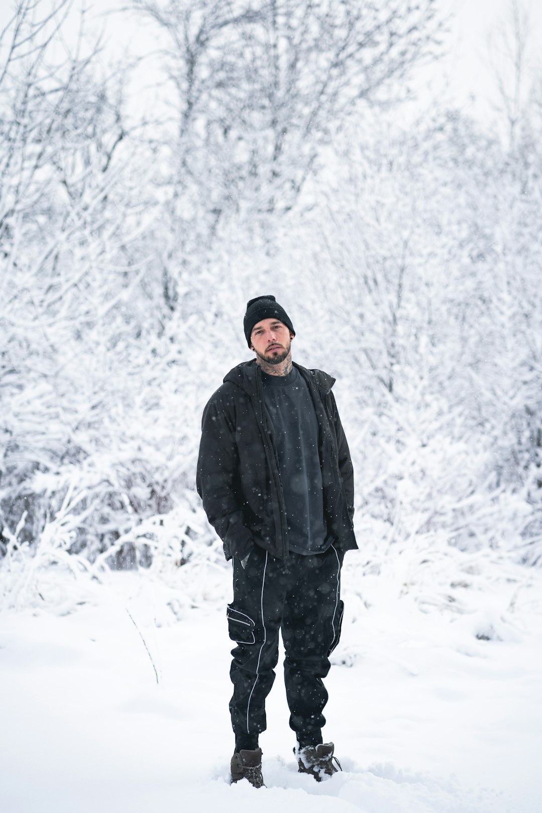 man in black jacket standing on snow covered ground