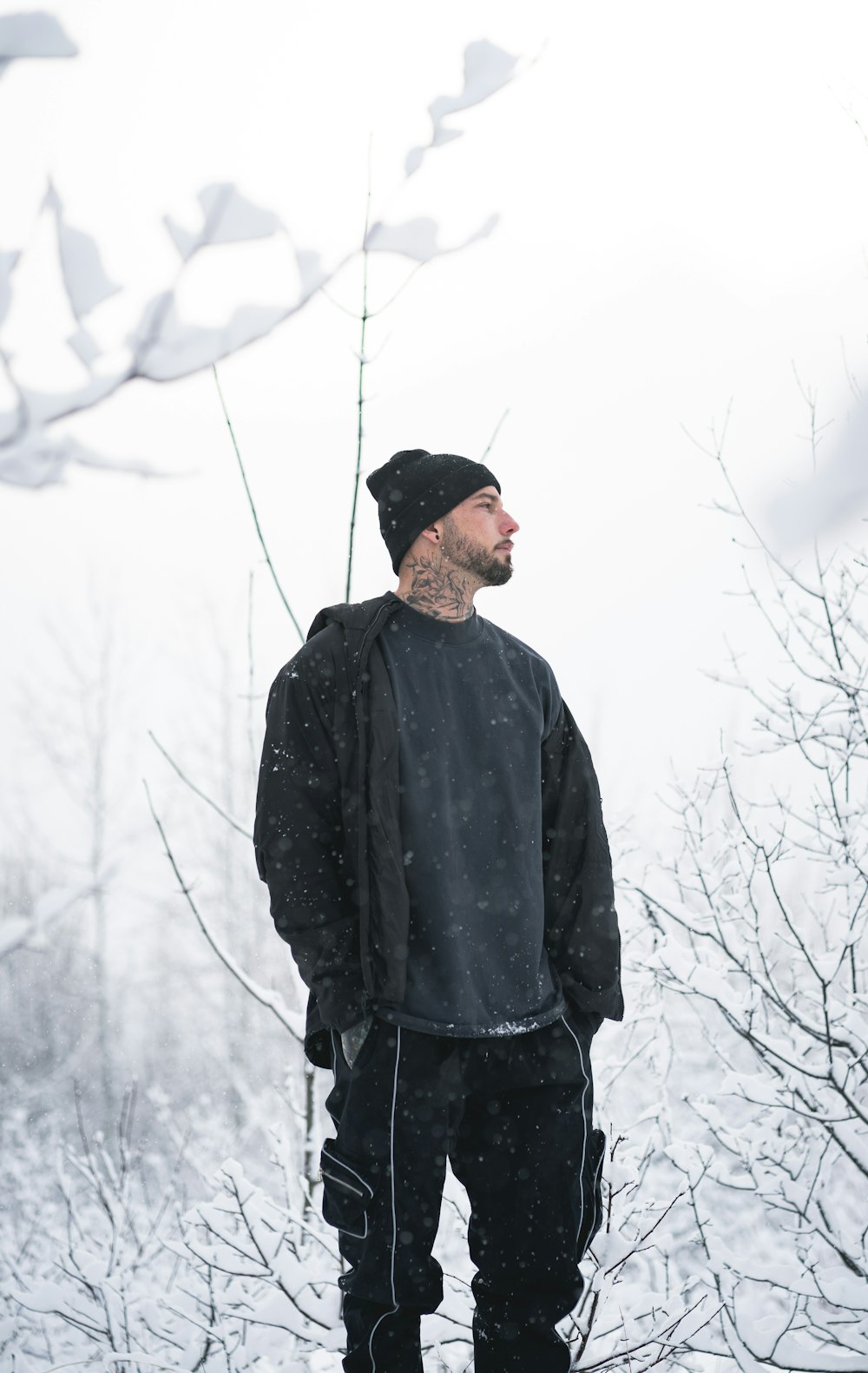 man in black jacket and black knit cap standing on snow covered ground during daytime