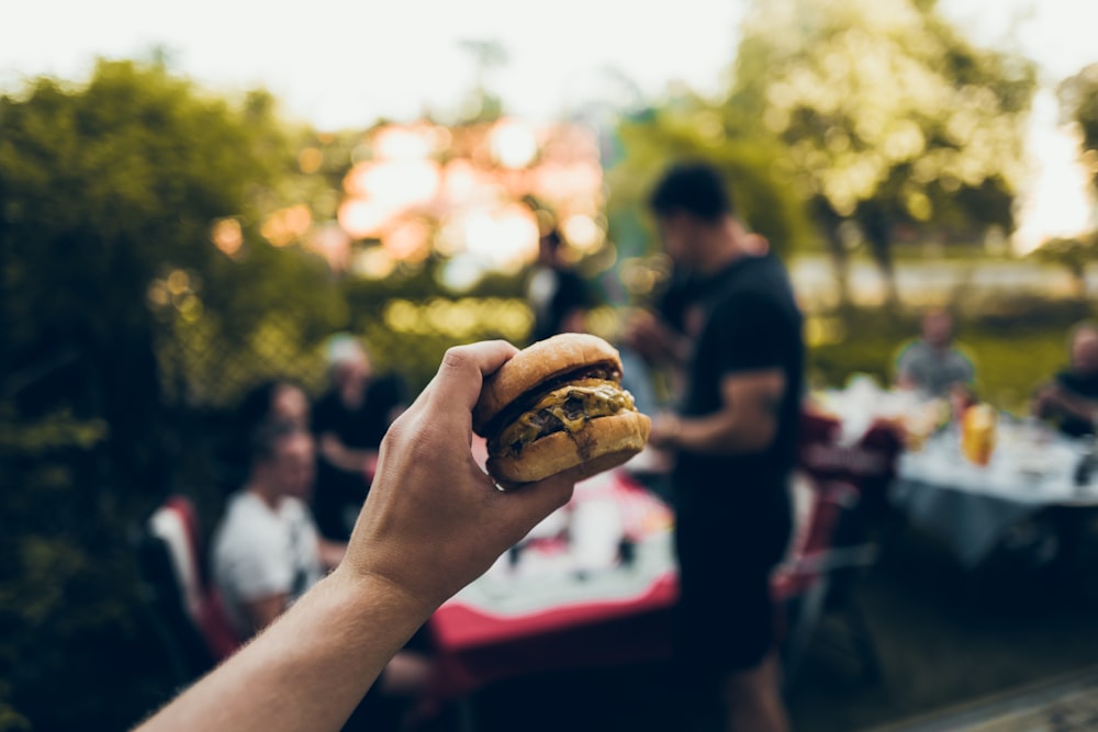 person holding burger with cheese