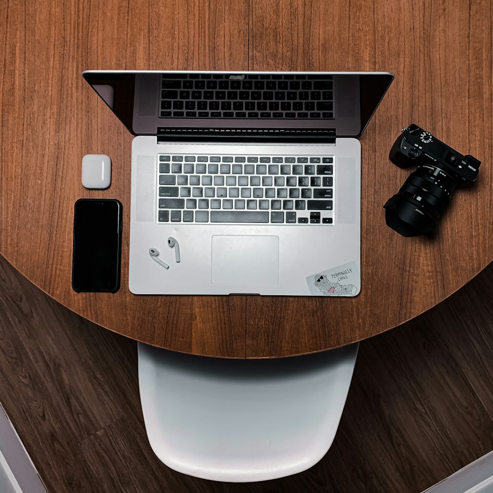 black and silver laptop computer beside black dslr camera on brown wooden table