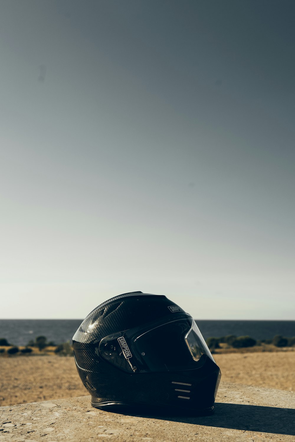 Casco de moto negro sobre arena marrón durante el día