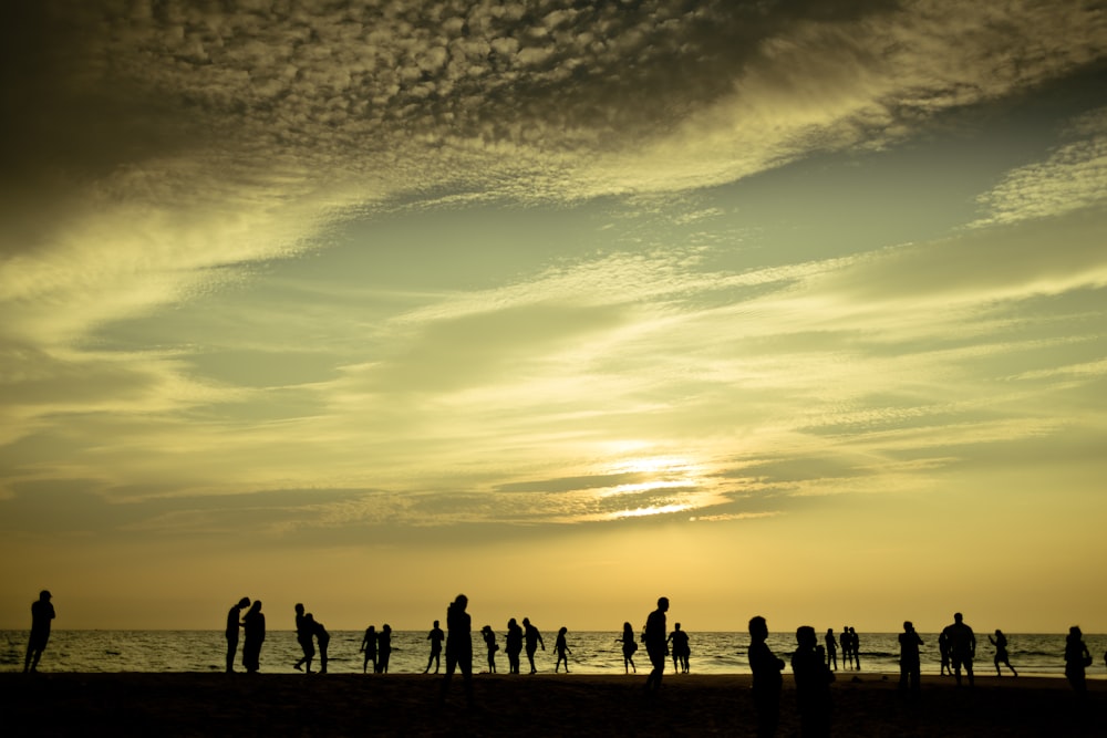 夕暮れ時の浜辺に立つ人々のシルエット