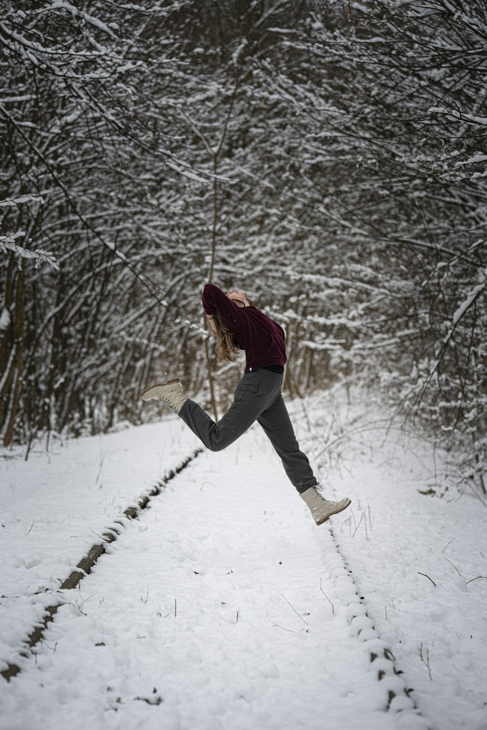 woman in red jacket and black pants standing on snow covered ground during daytime