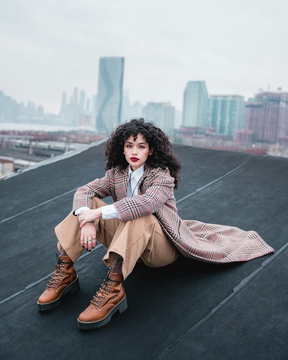 woman in brown coat sitting on black asphalt road during daytime