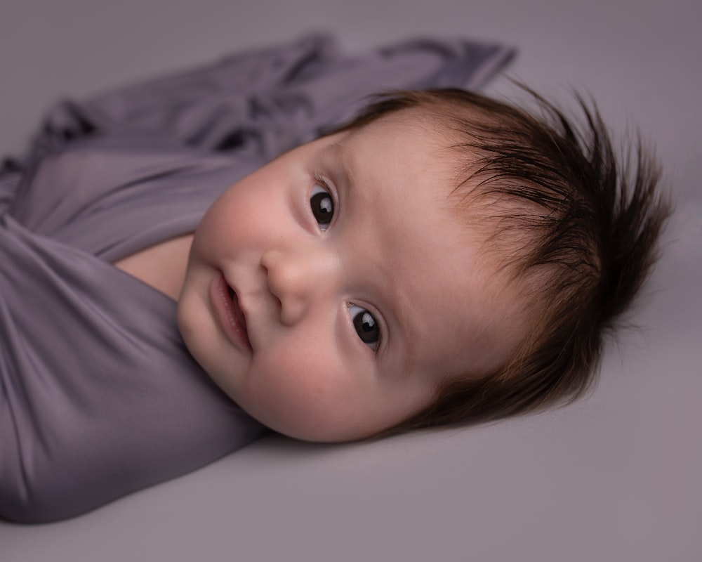 baby in white shirt lying on bed