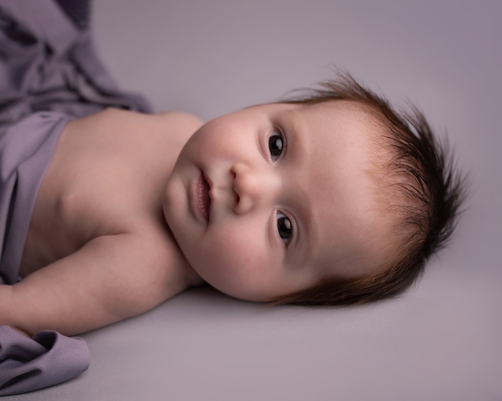 baby lying on white bed