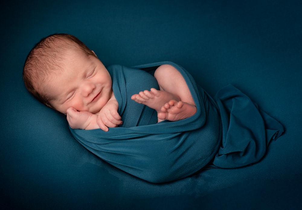 baby lying on blue textile