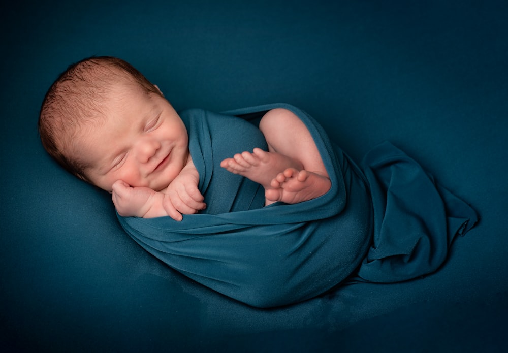 bebé acostado sobre textil azul