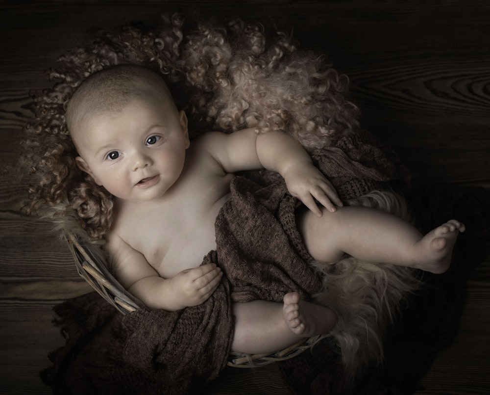 baby lying on brown textile