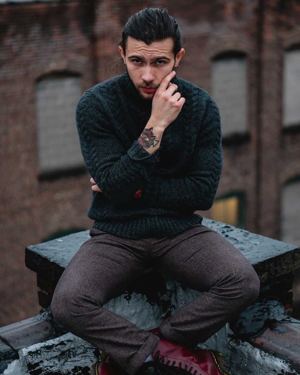 man in black sweater and gray pants sitting on brown wooden bench
