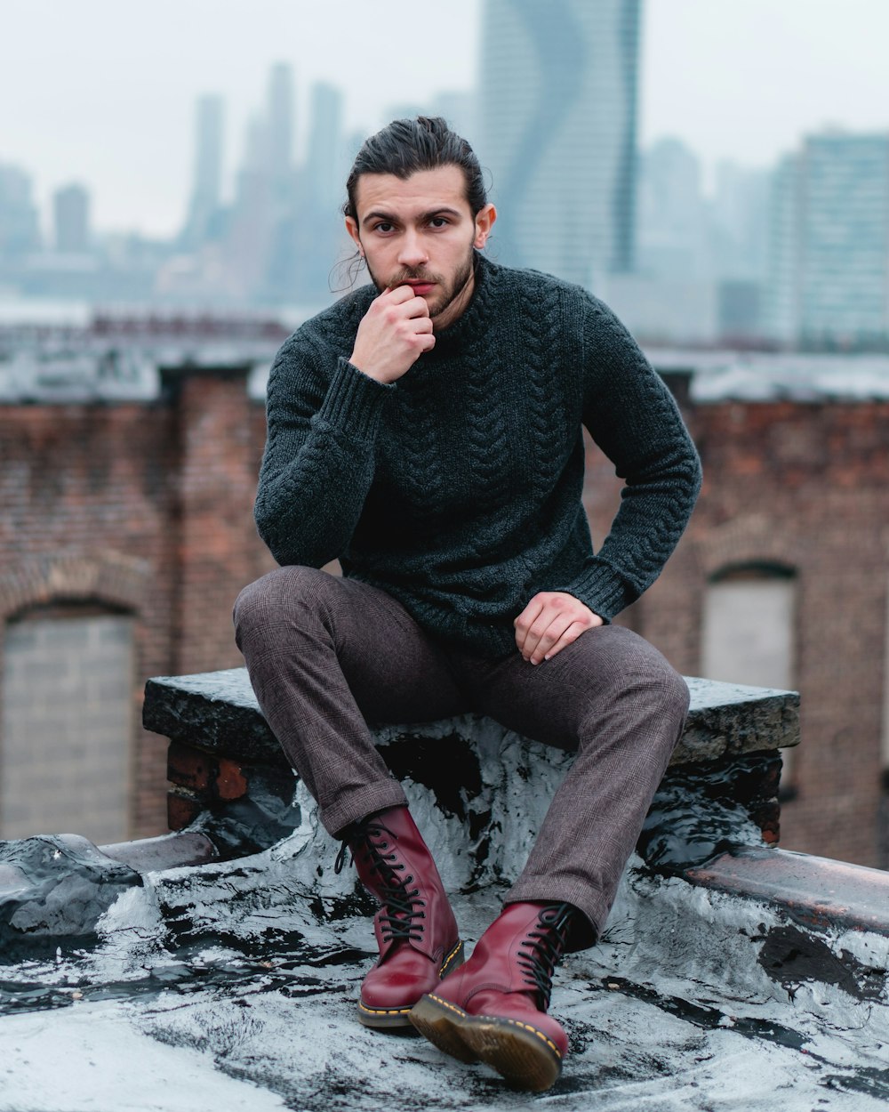 man in black sweater and brown pants sitting on brown wooden bench