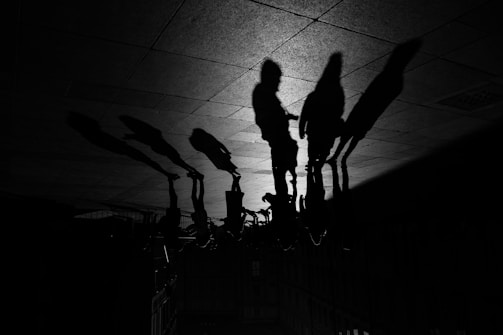 Silhouettes of several people cast on the ground, creating elongated shadows against a textured surface.