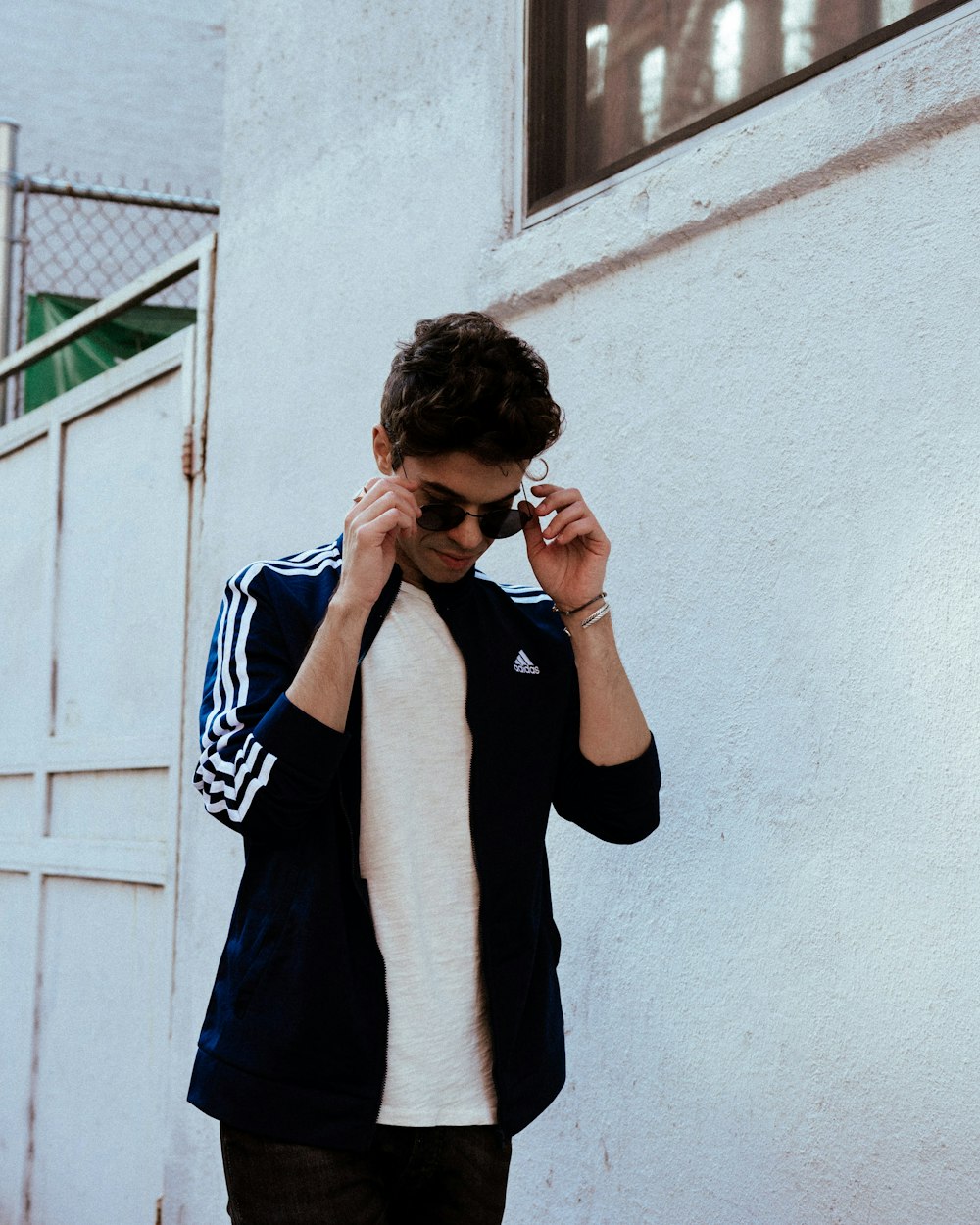 man in black and white long sleeve shirt leaning on white wall