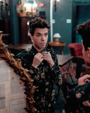 A player adjusting a richly decorated doublet in front of a mirror.