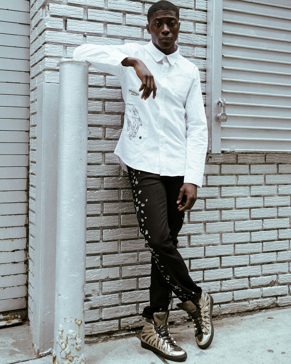 man in white dress shirt and black pants standing beside white wall