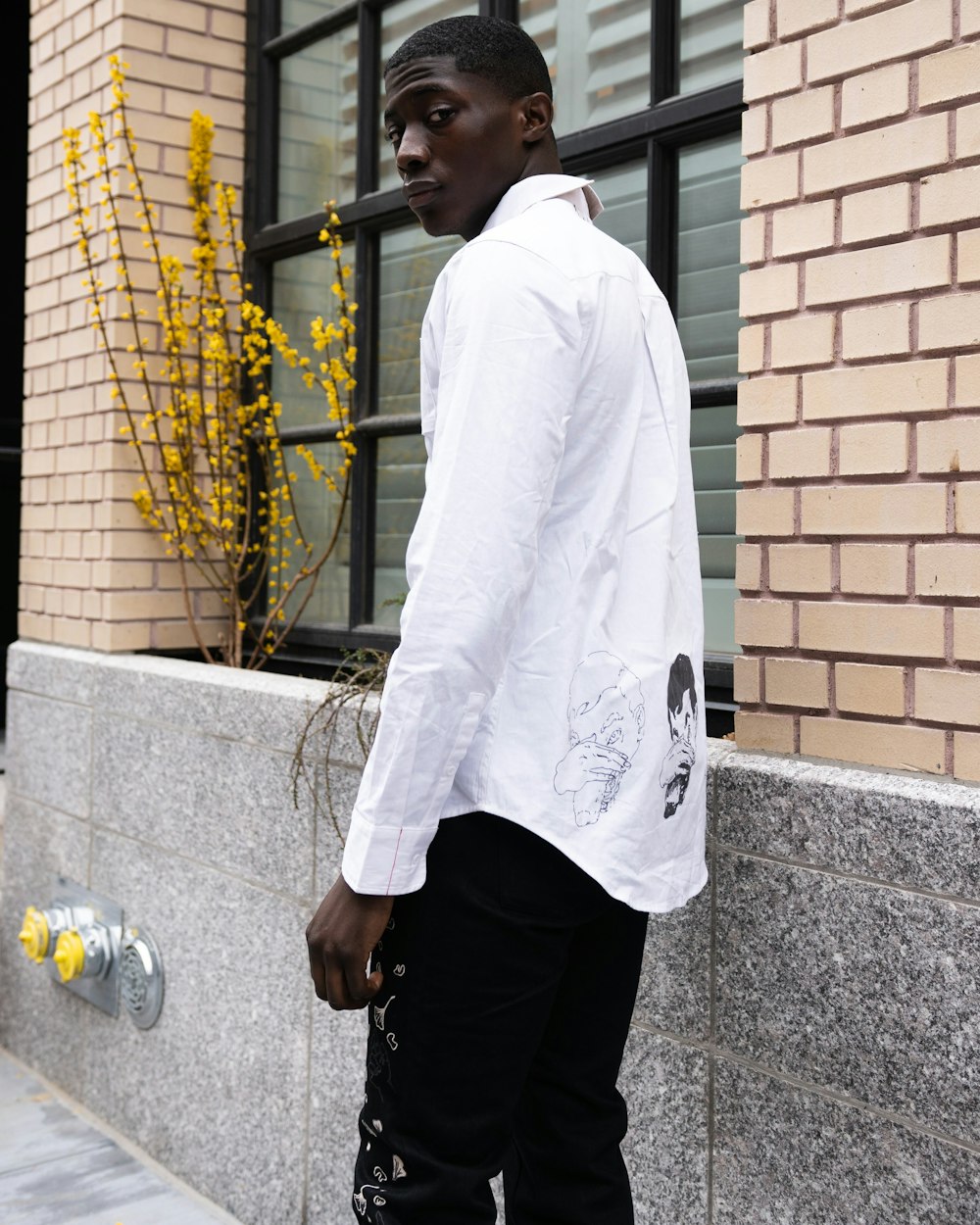 uomo in camicia bianca e pantaloni neri in piedi accanto al muro di mattoni  marroni durante il giorno foto – Stile Immagine gratuita su Unsplash
