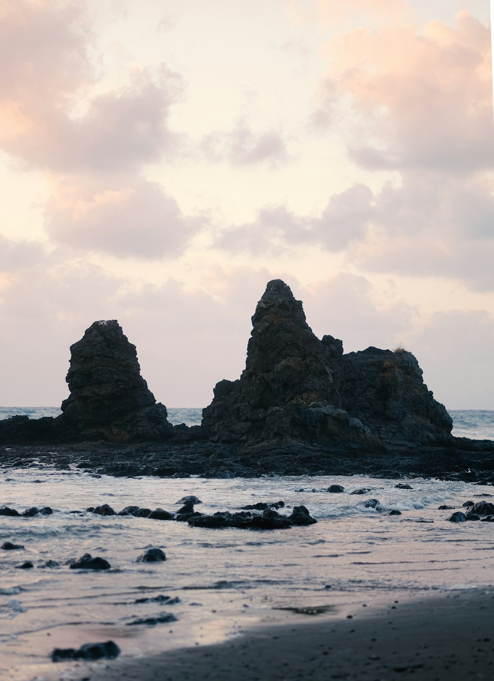 brown rock formation on sea under white clouds during daytime